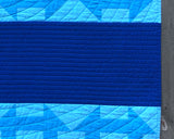Detail of binding of Minimalist Churn Dash quilt, showing matched dark blue binding to the dark blue section of the quilt